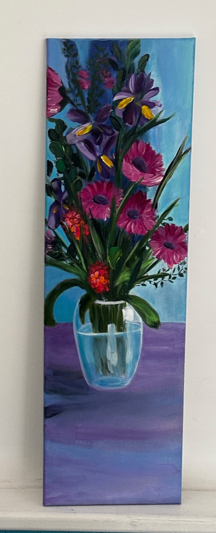 Painting of  pink and purple flowers in a glass vase on a blue background