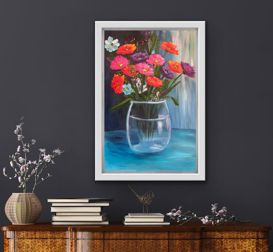 Framed original painting of a vase with colourful flowers on a dark wall above a wooden cabinet.